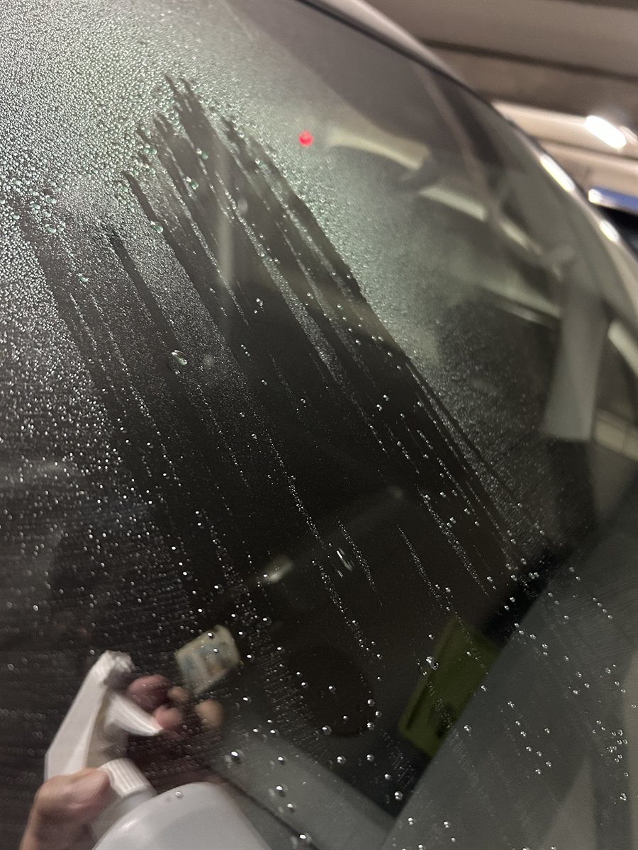 霧吹きで水をかけた直後のフロントガラス。水が筋になって流れ落ちている